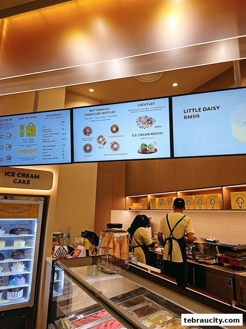 Interior view of an ice cream shop with staff preparing orders and a display of ice cream cakes.
