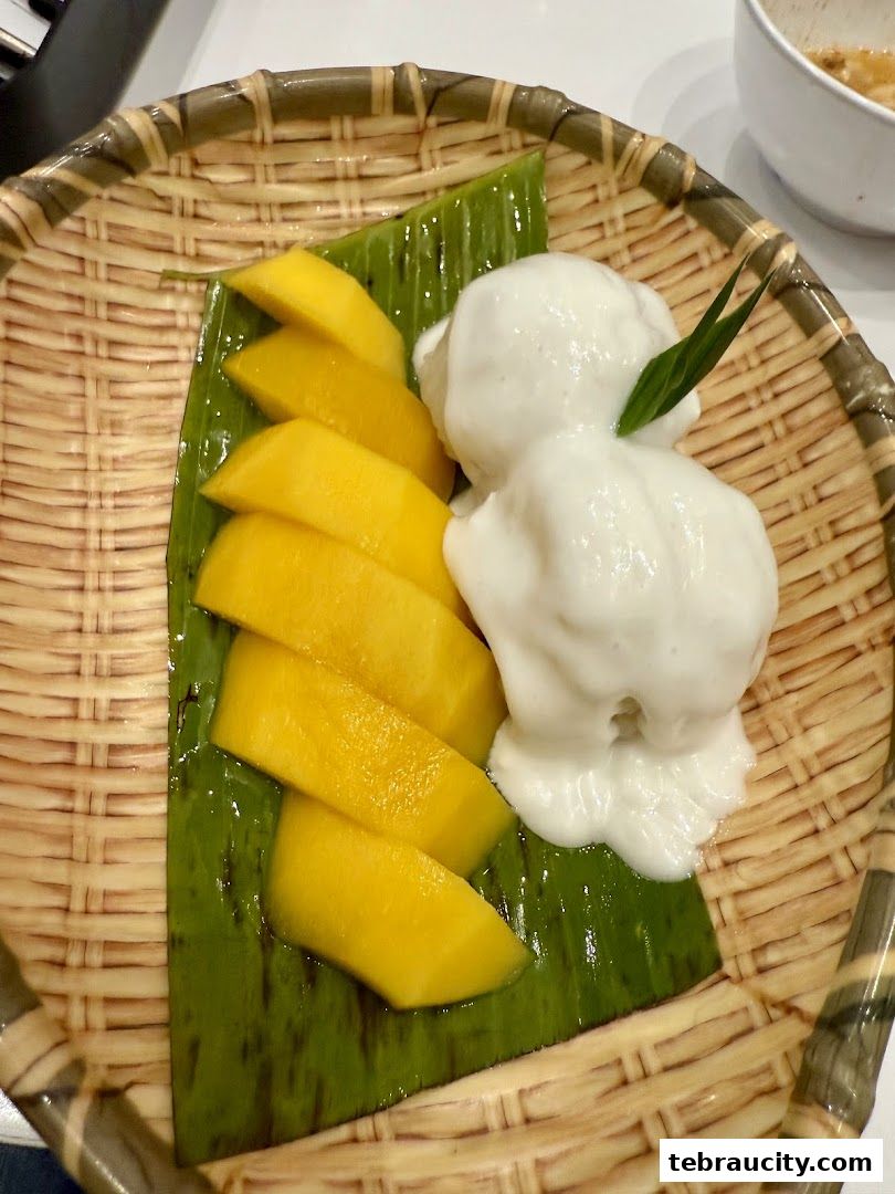 A close-up of a delicious Thai dessert with sliced mango and coconut ice cream.