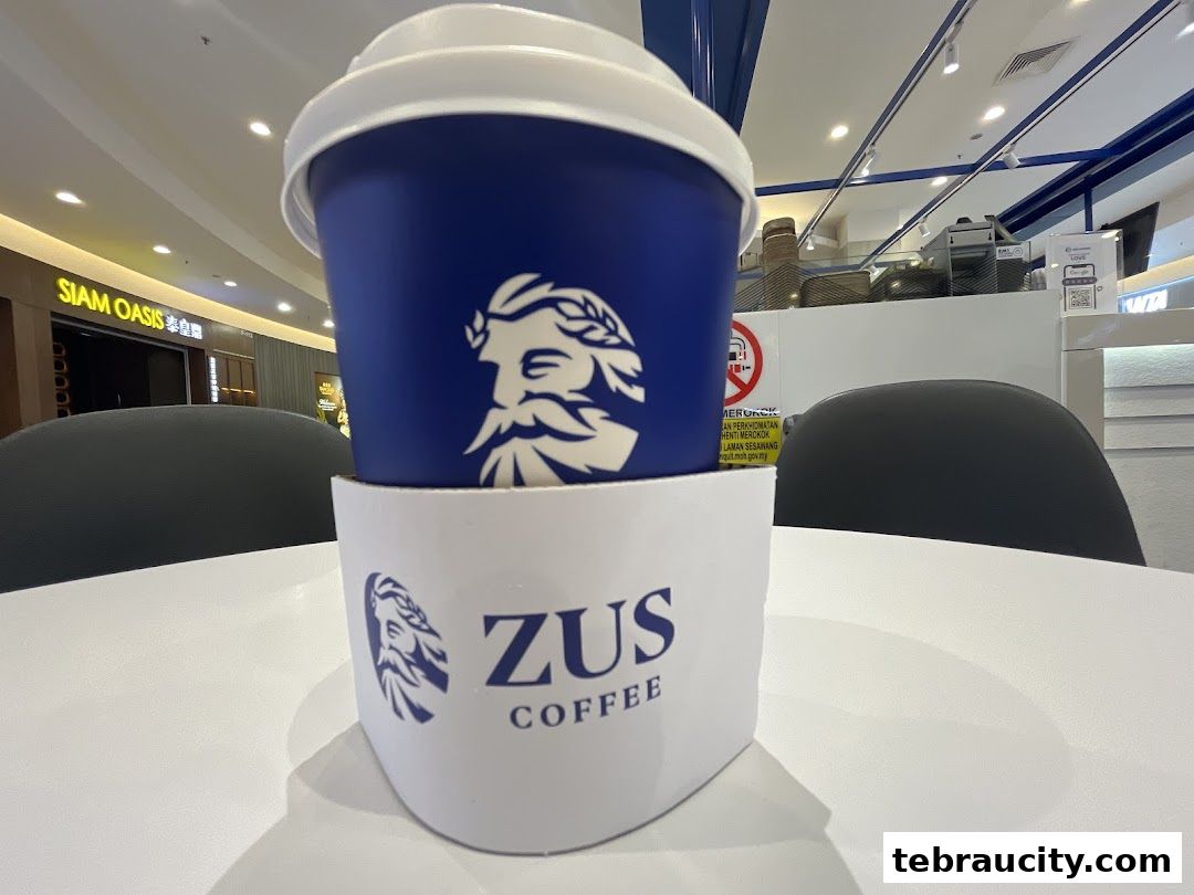 A close-up of a ZUS Coffee cup with the shop's logo on a table.