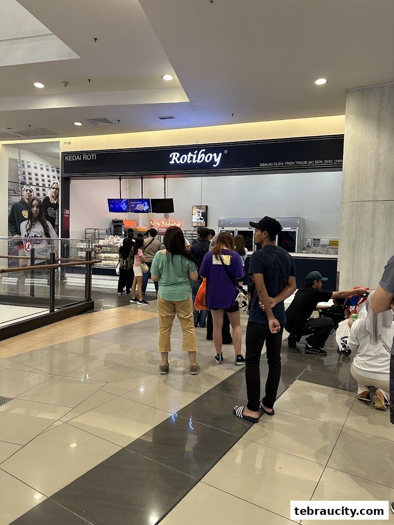 People queuing outside a Rotiboy shop with a "Now Baking" sign.