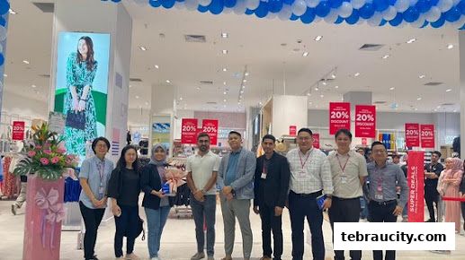 A group of people posing for a photo inside a LC Waikiki store with balloons and discount signs.