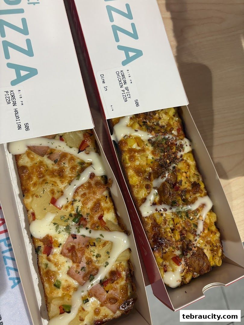 Two boxes of pizza slices, one Hawaiian and one Korean Spicy Chicken.