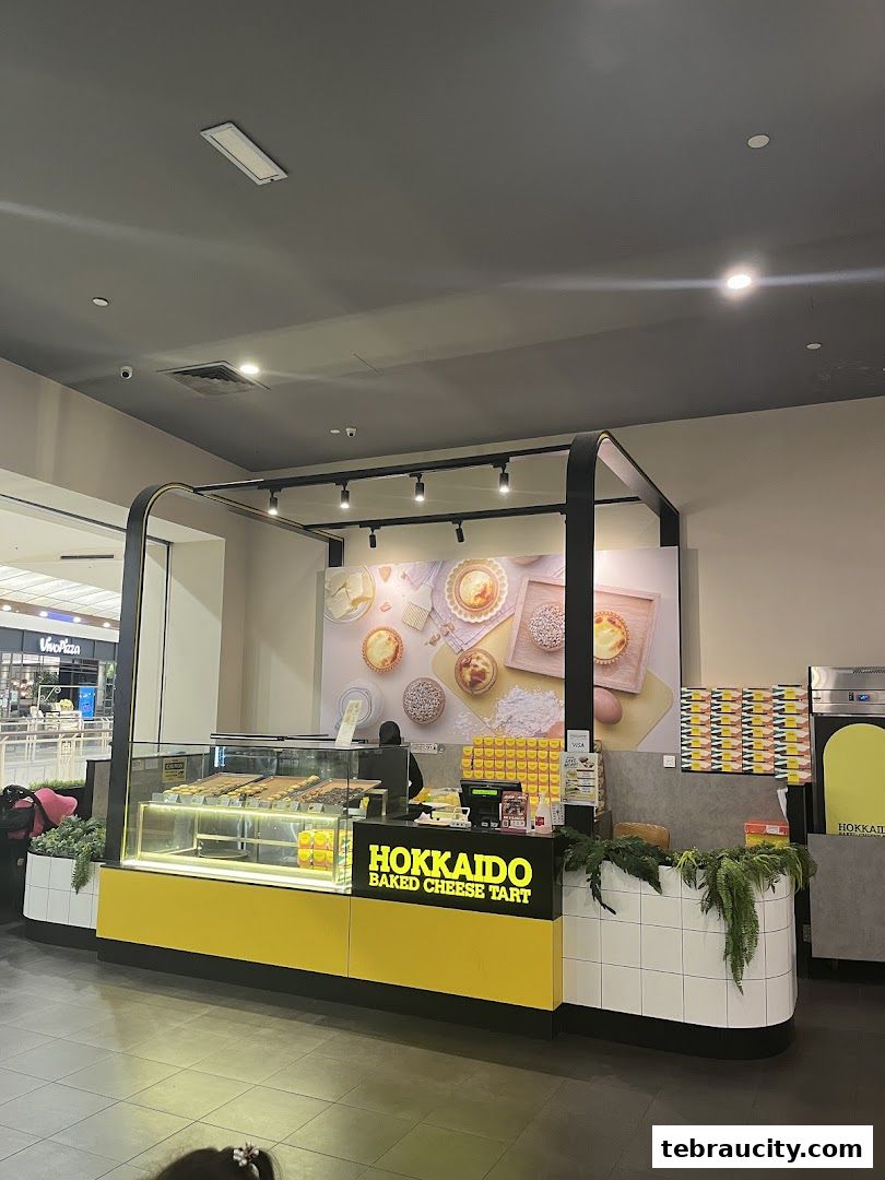 A Hokkaido Baked Cheese Tart shop counter with tarts displayed in a refrigerated case.