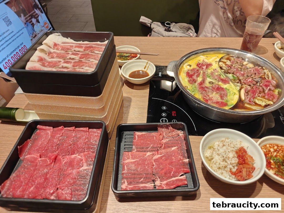 A table laden with fresh raw meat slices and a bubbling hot pot, ready for a delicious meal.