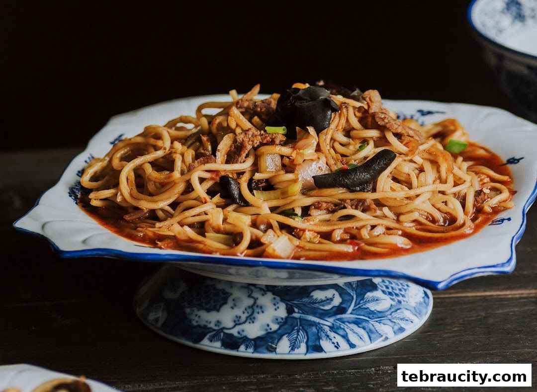 A close-up shot of a delicious noodle dish with meat and mushrooms, served on a decorative plate.