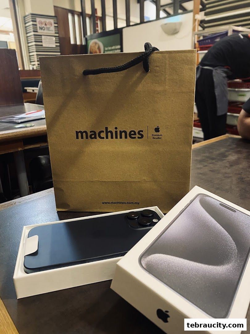 A Machines Apple Reseller shopping bag and an iPhone in its box on a table.
