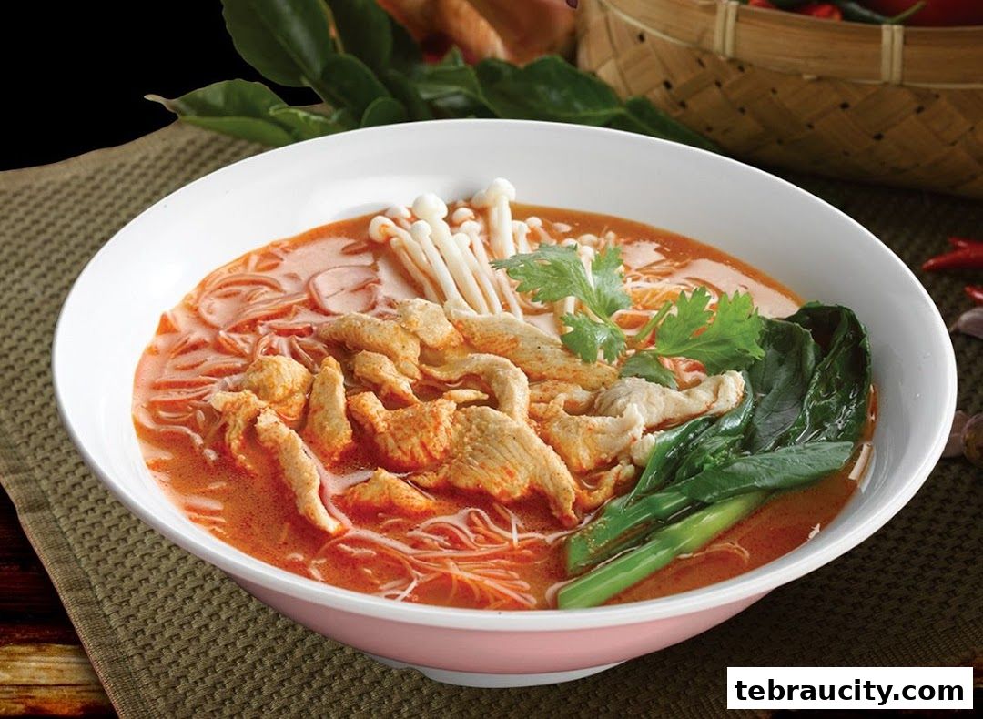 A bowl of delicious noodle soup with chicken, mushrooms, and greens.