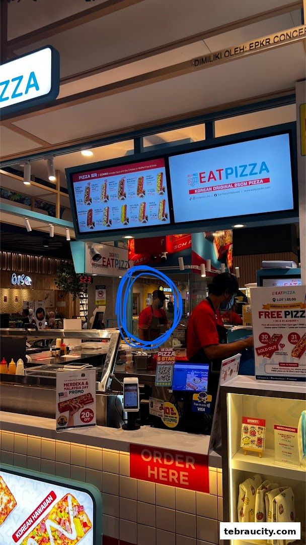 A view of the Eat Pizza counter with staff, menu boards, and promotional displays.