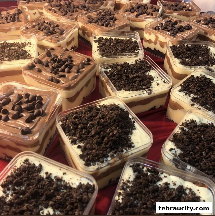 A close-up shot of many individual dessert containers filled with creamy layers and topped with chocolate chips or cookie crumbs.