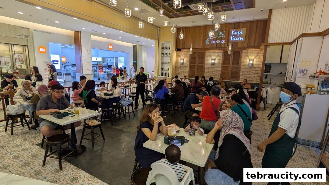 A busy cafe with many customers dining and a staff member serving.