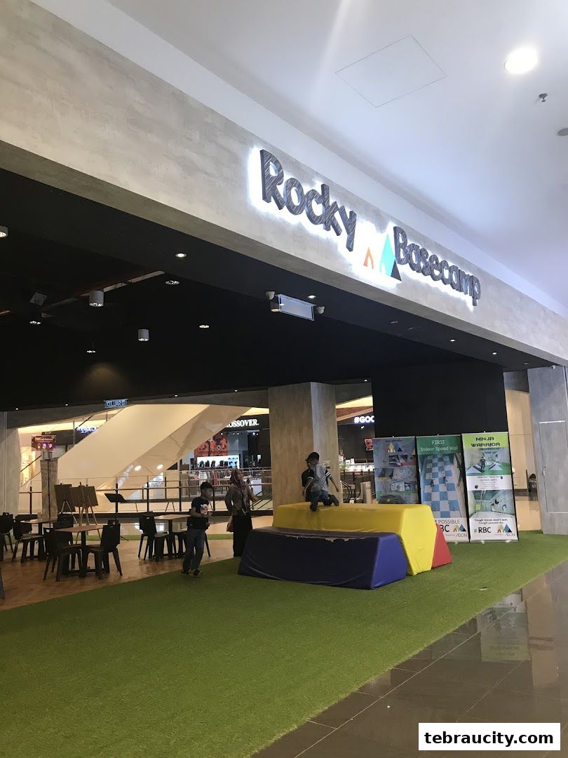 Rocky Basecamp shop entrance with children playing on soft obstacles and promotional posters.