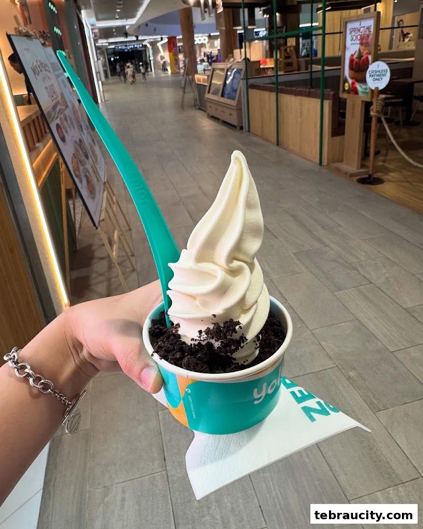 A hand holds a cup of soft-serve ice cream with cookie crumbles.