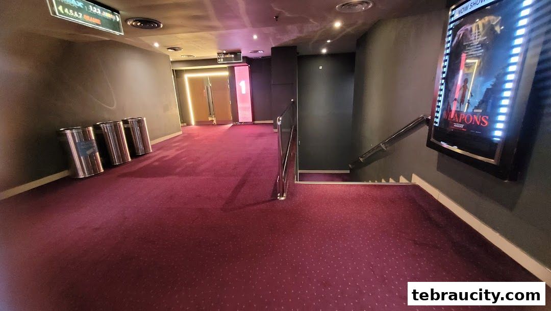 A cinema hallway with a movie poster and stairs leading down.