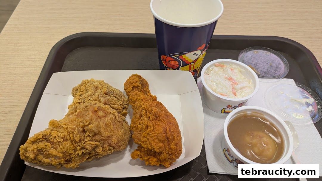 A tray of fried chicken, coleslaw, mashed potatoes with gravy, and a drink.
