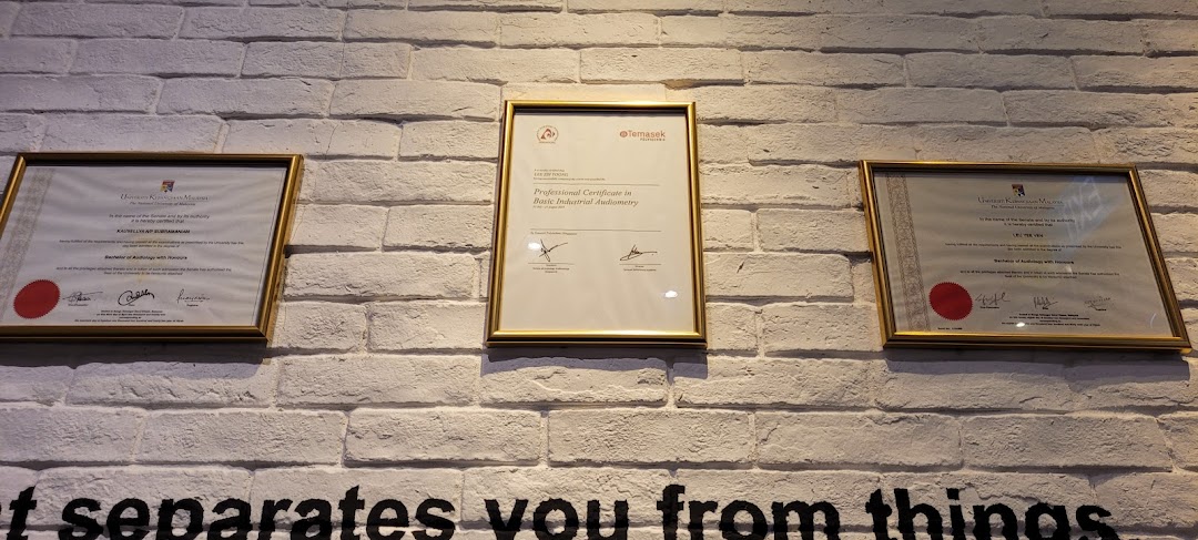 Framed audiology and industrial audiometry certificates displayed on a white brick wall.