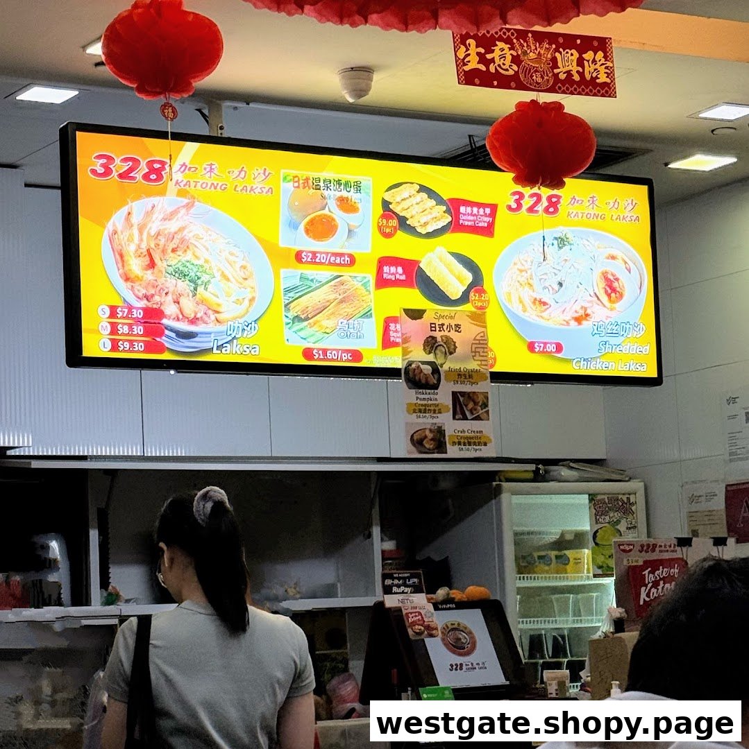 A digital menu board displaying various laksa dishes and side orders at 328 Katong Laksa.