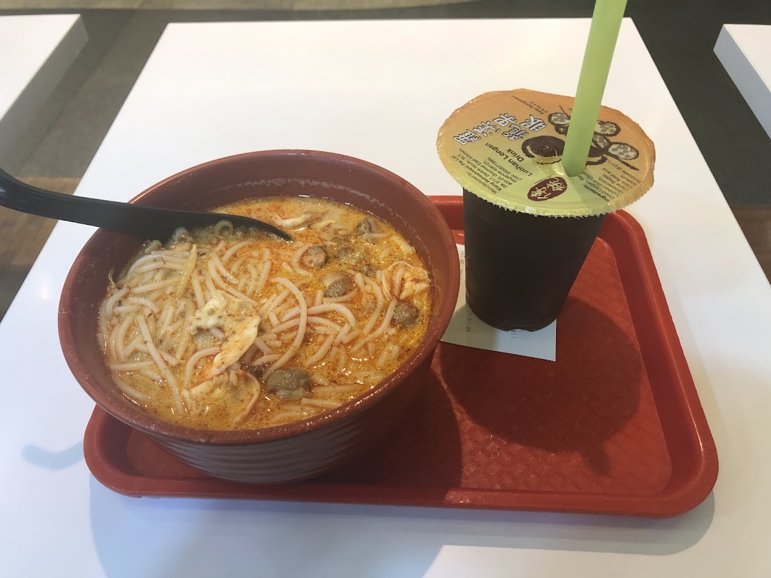 A bowl of authentic Katong Laksa with a refreshing drink served on a red tray.