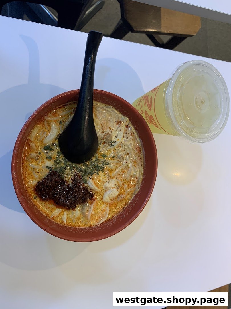 A vibrant bowl of Katong Laksa with a side drink, showcasing the rich broth and fresh ingredients.