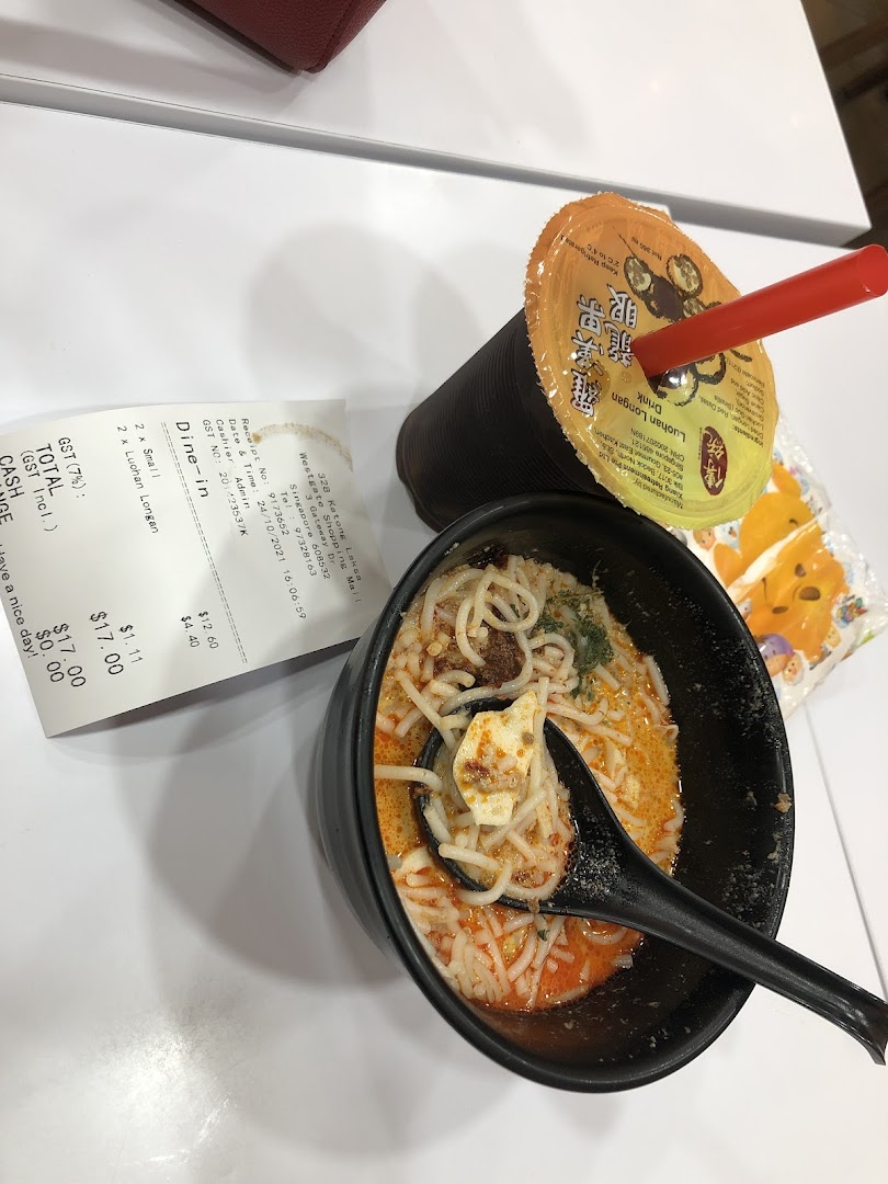 A bowl of Katong Laksa with a refreshing drink and receipt on a white table.