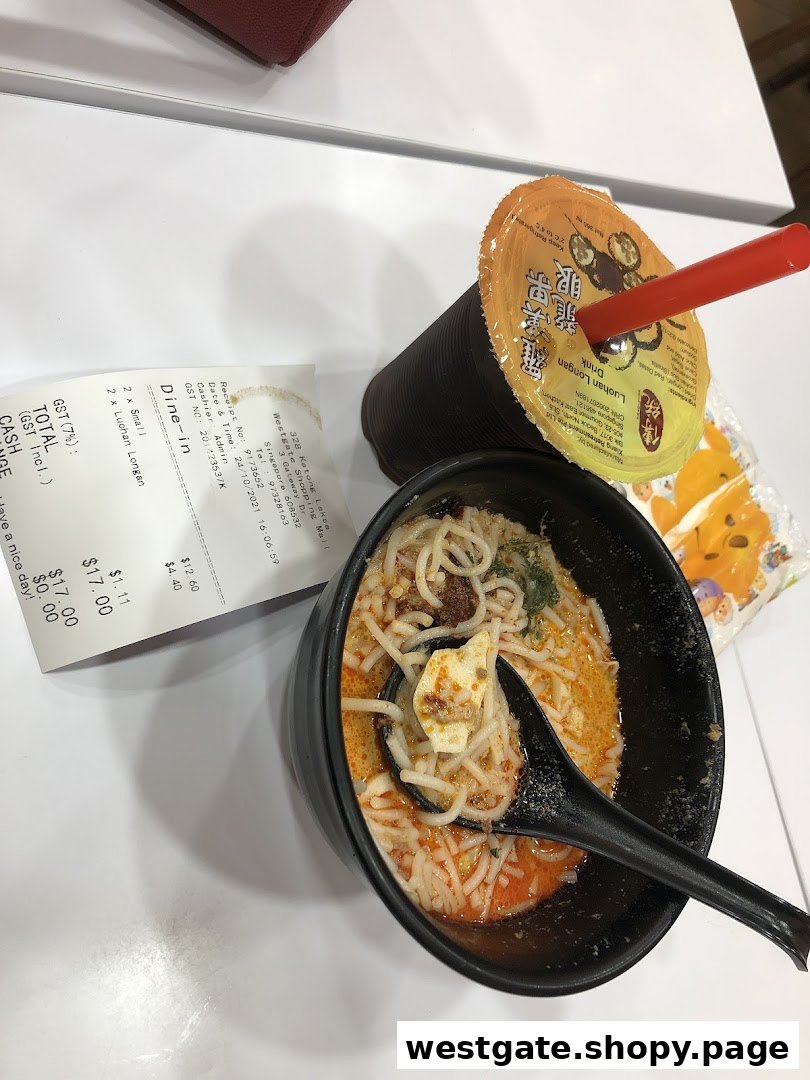 A bowl of Katong Laksa with a refreshing drink and receipt on a white table.