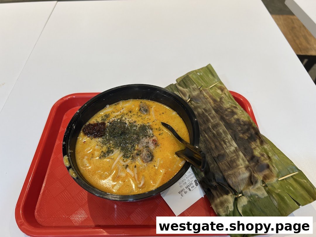 A vibrant bowl of Katong Laksa with grilled otah on a red tray.