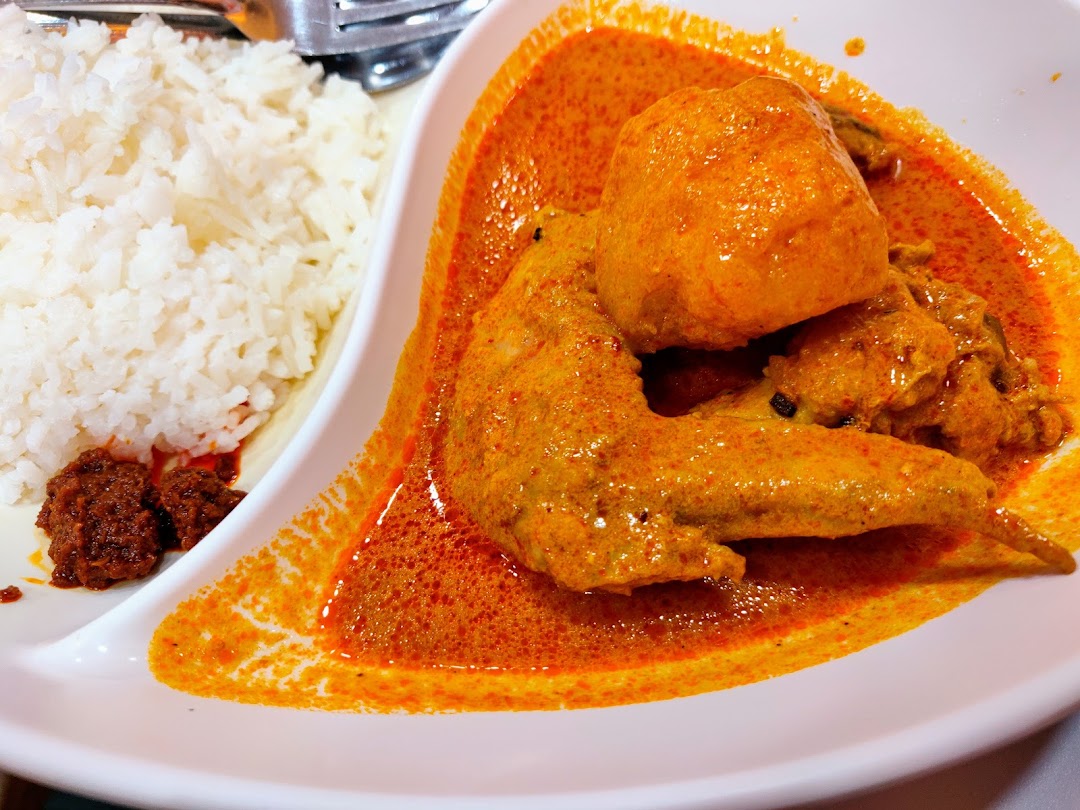 A vibrant plate of chicken curry with rice and sambal, showcasing a delicious meal.