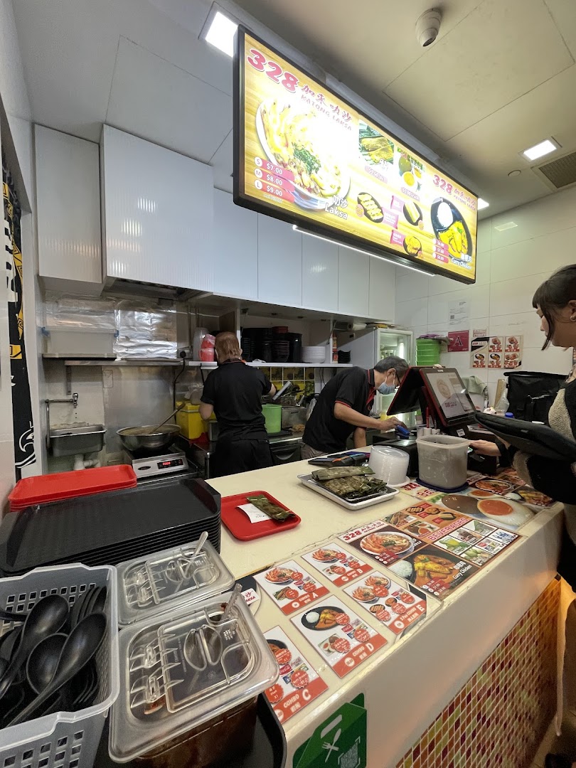 A bustling interior view of 328 Katong Laksa, showing staff, counter, and menu displays.
