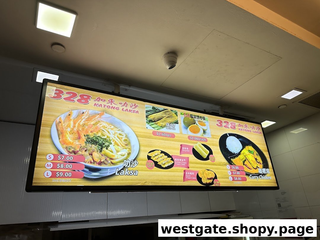 A bright digital menu board showcasing 328 Katong Laksa's signature dishes and side orders with prices.