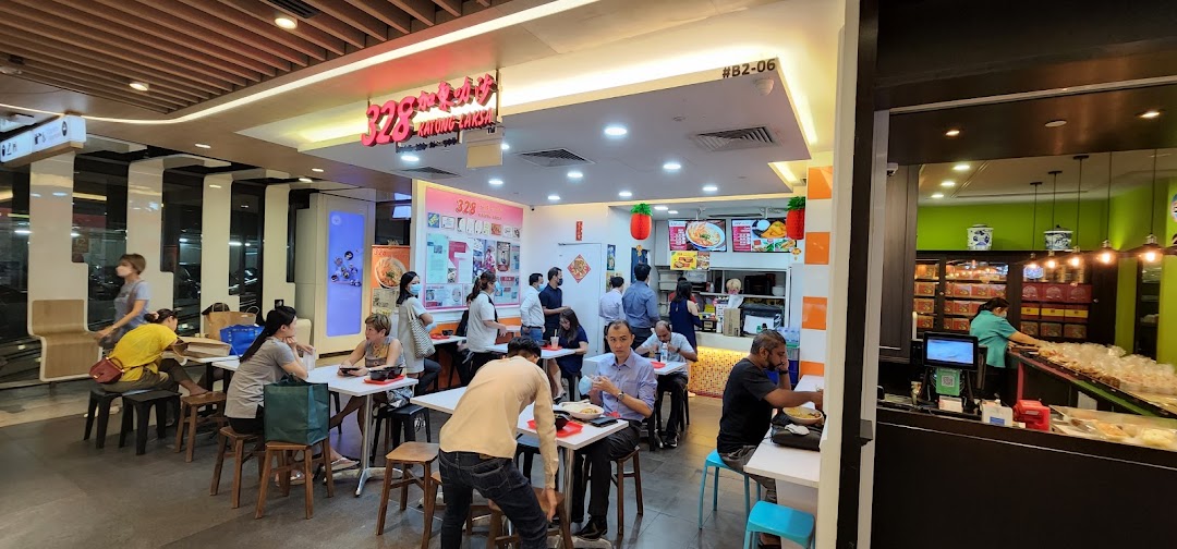 A bustling interior view of 328 Katong Laksa with customers dining and staff at the counter.