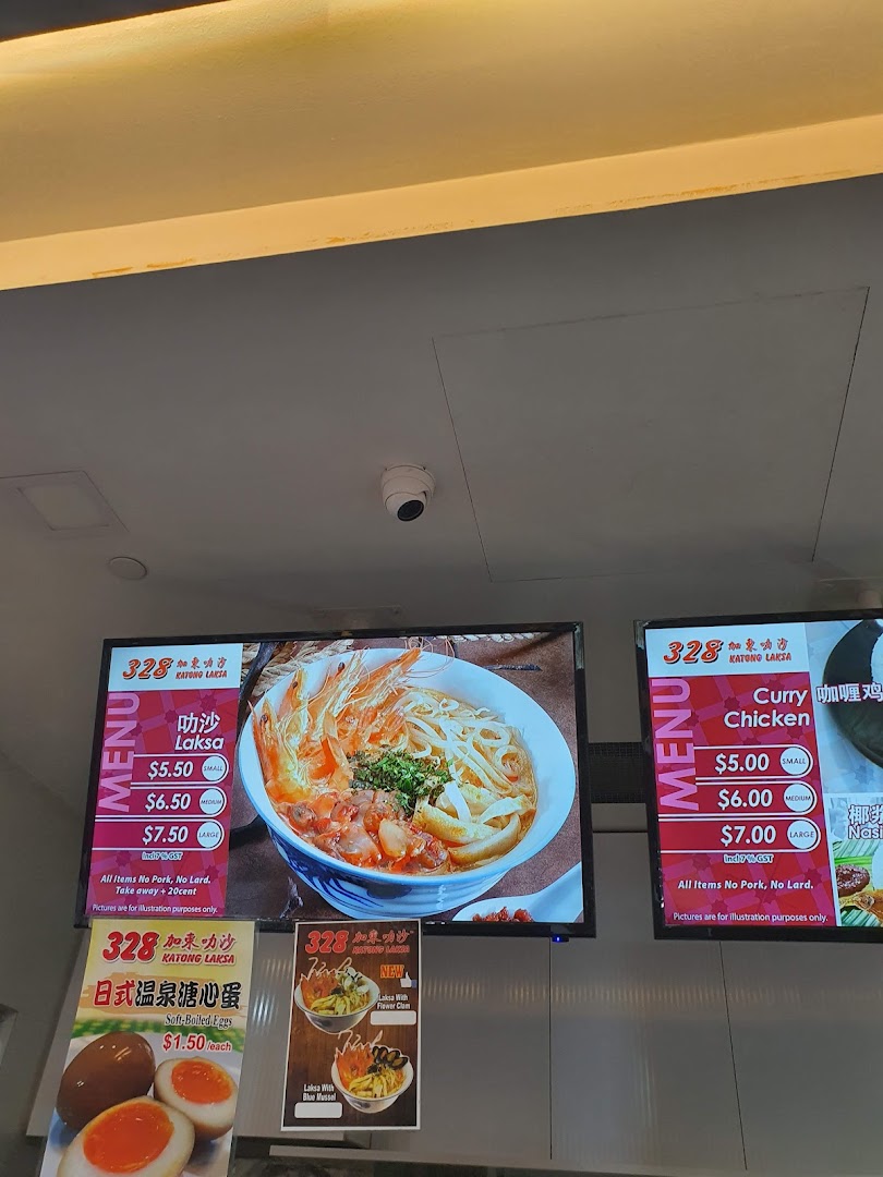 Digital menu boards and signs displaying Laksa, Curry Chicken, and side dishes with prices.