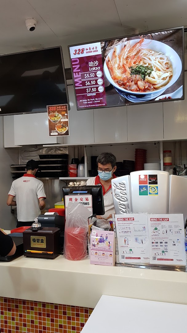 Staff at the counter of 328 Katong Laksa with a digital menu display.
