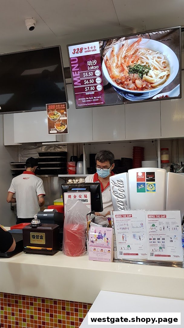 Staff at the counter of 328 Katong Laksa with a digital menu display.