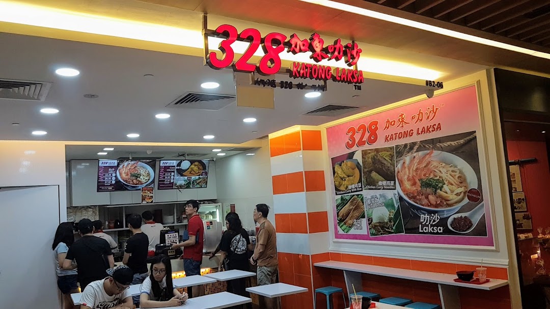 Interior view of 328 Katong Laksa, showing customers, counter, and large menu displays featuring their famous laksa.