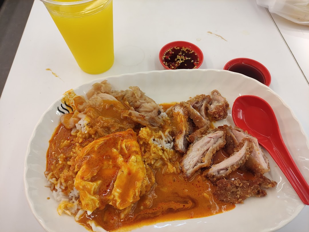 A plate of rice with fried chicken, braised meat, and curry egg, served with sauces and a drink.
