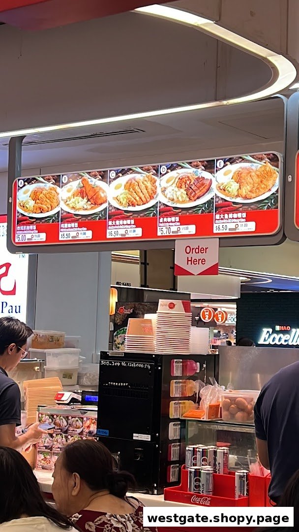 A digital menu board displaying various curry rice dishes with prices above a bustling food stall counter.