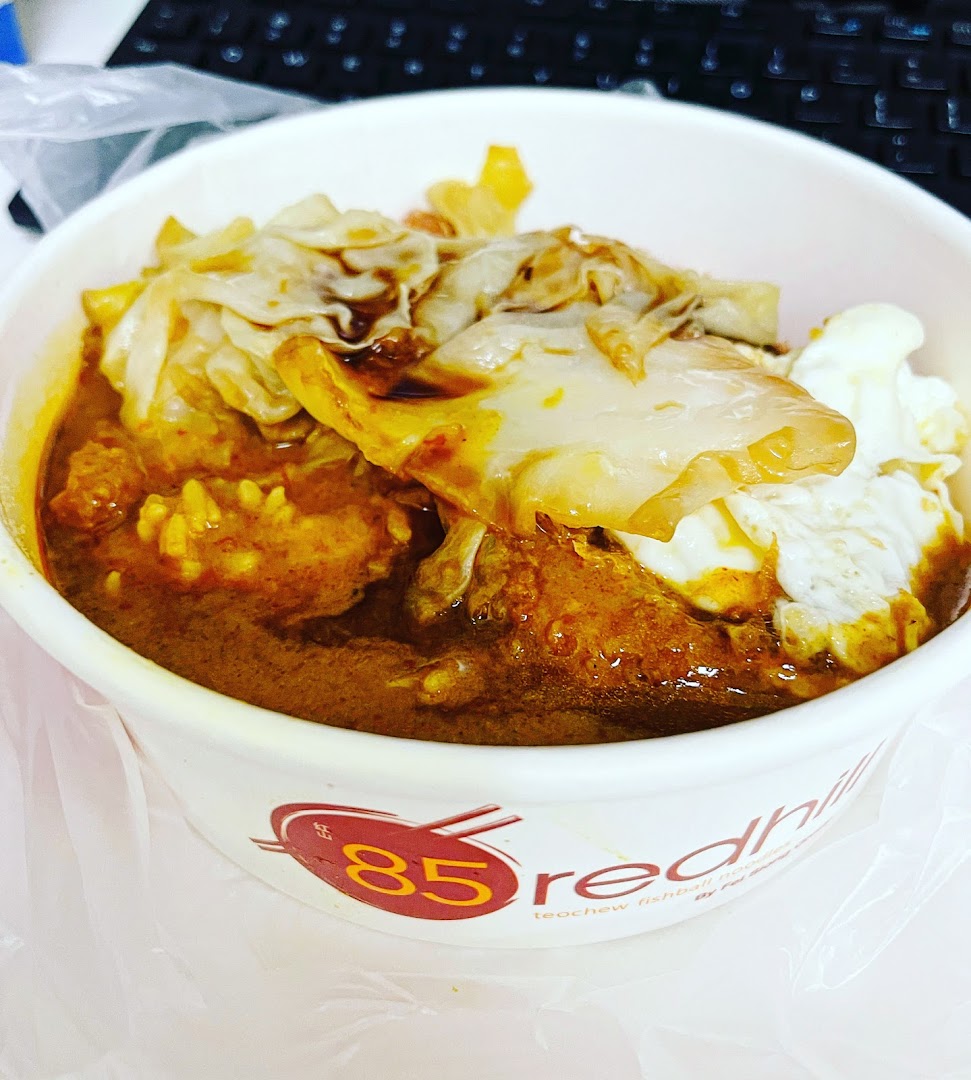 A close-up of a delicious bowl of curry noodles or rice with fishballs and egg from 85 Redhill Teochew Fishball Noodles.