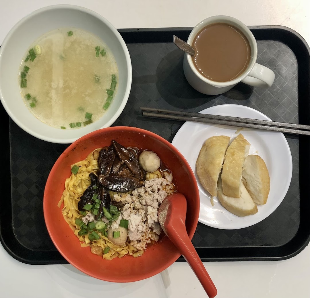 A delicious meal featuring Teochew fishball noodles, soup, fishcake, and a hot beverage on a tray.