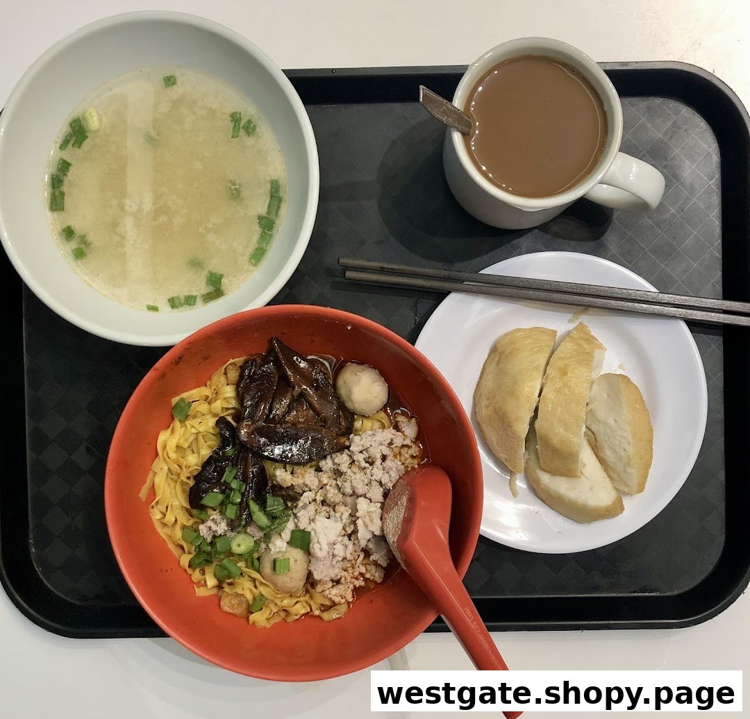 A delicious meal featuring Teochew fishball noodles, soup, fishcake, and a hot beverage on a tray.