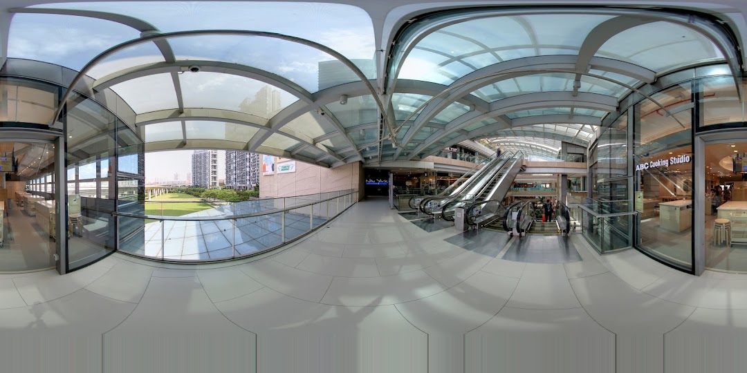Panoramic view of a modern shopping mall interior with escalators and ABC Cooking Studio entrance.