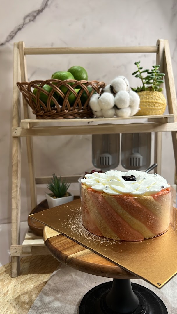 A beautifully decorated cake on a wooden stand, surrounded by kitchen decor and fresh ingredients.