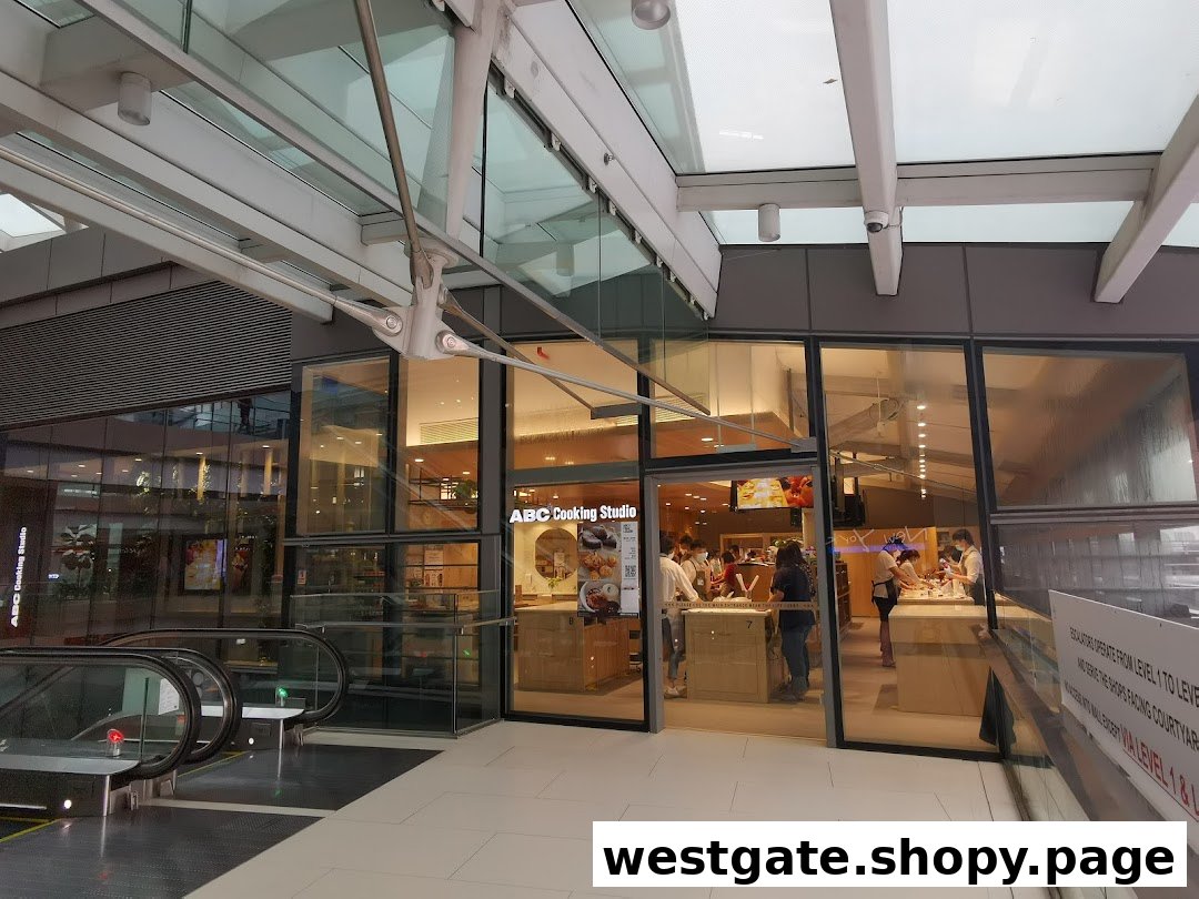 The glass facade of ABC Cooking Studio with people inside, located next to escalators in a mall.