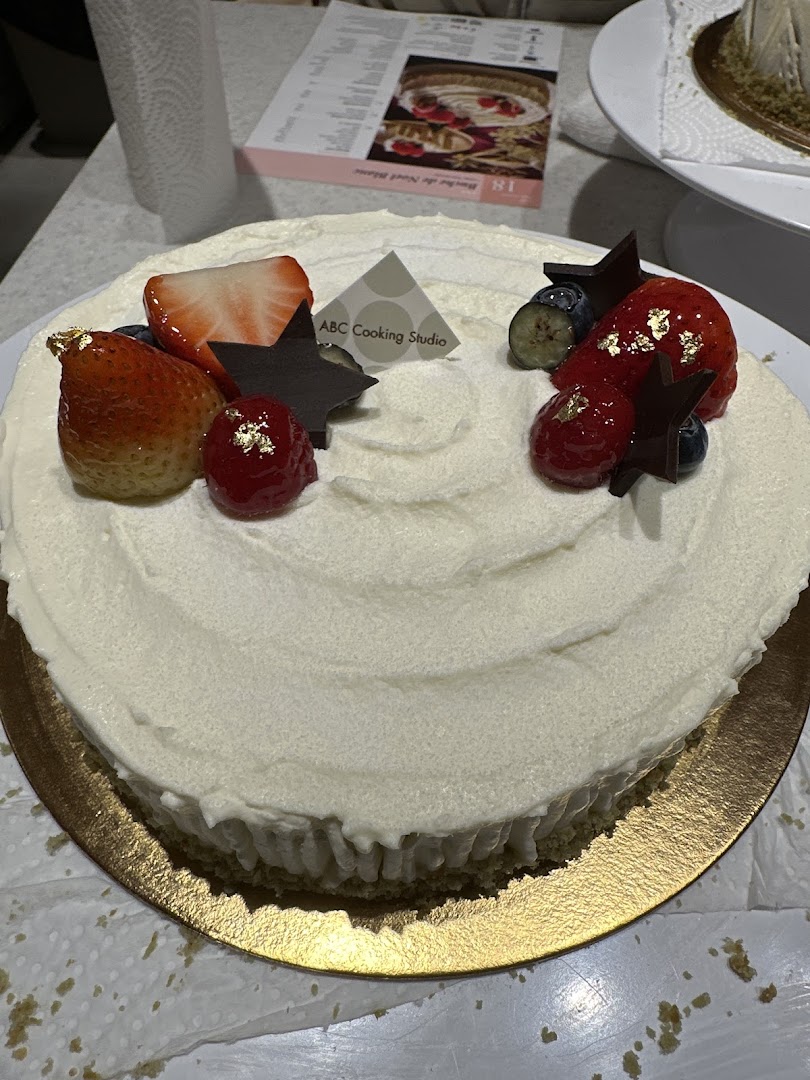 A beautifully decorated cake with fresh berries, chocolate stars, and gold leaf, made at ABC Cooking Studio.