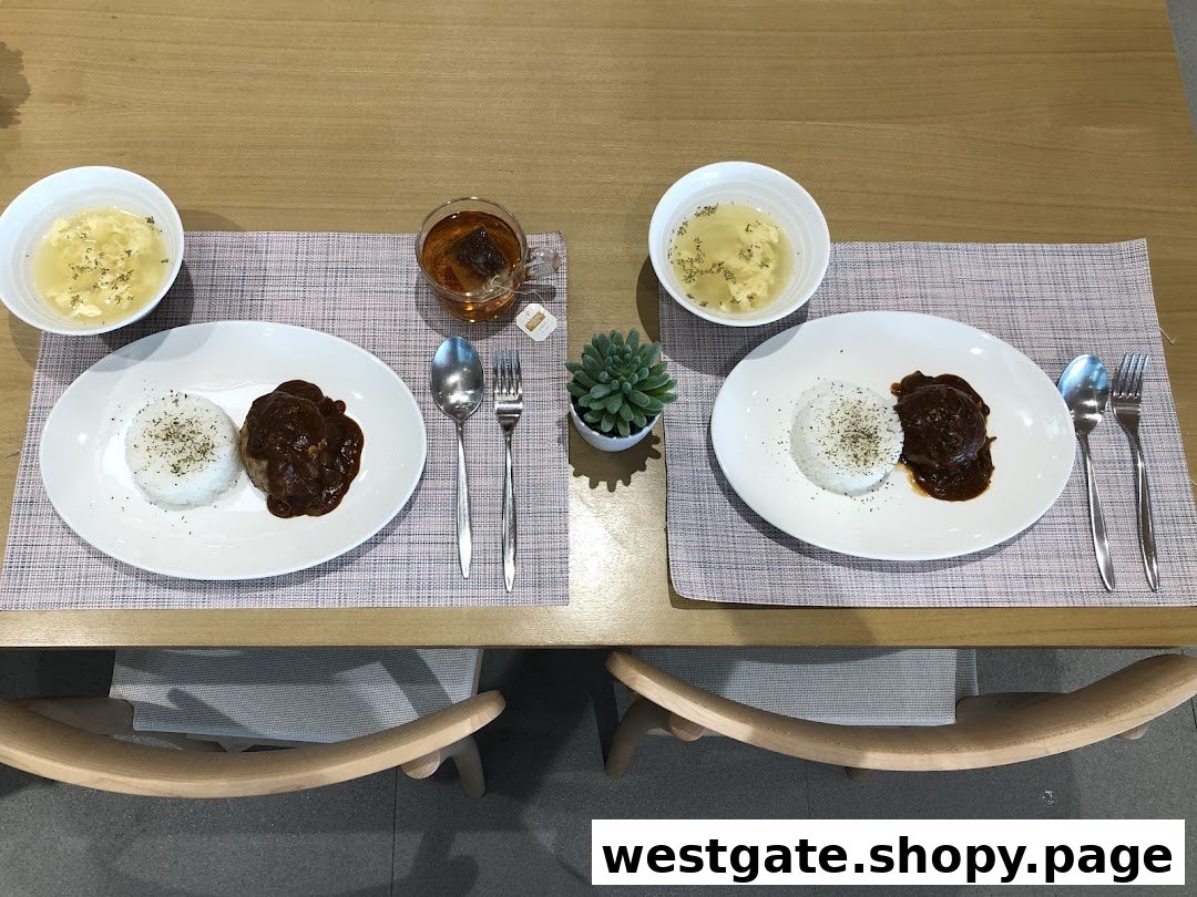 Two plates of hamburger steak with rice, soup, and tea, set on a wooden table.