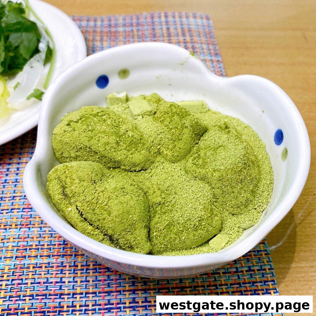 A bowl of green mochi-like desserts, generously coated with matcha powder, on a colorful placemat.