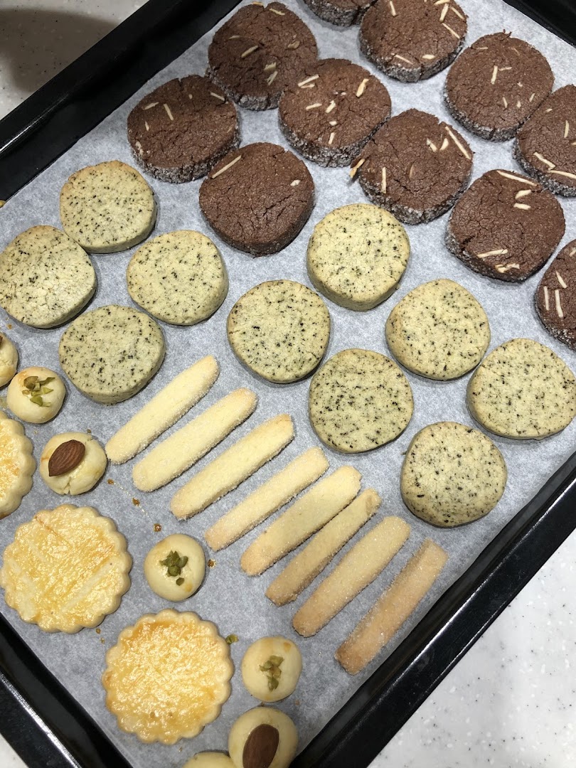 A baking tray filled with various freshly baked cookies, including chocolate, shortbread, and decorated varieties.