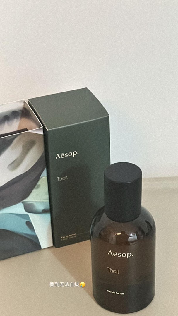 An Aesop Tacit Eau de Parfum bottle and its packaging box are displayed on a surface.