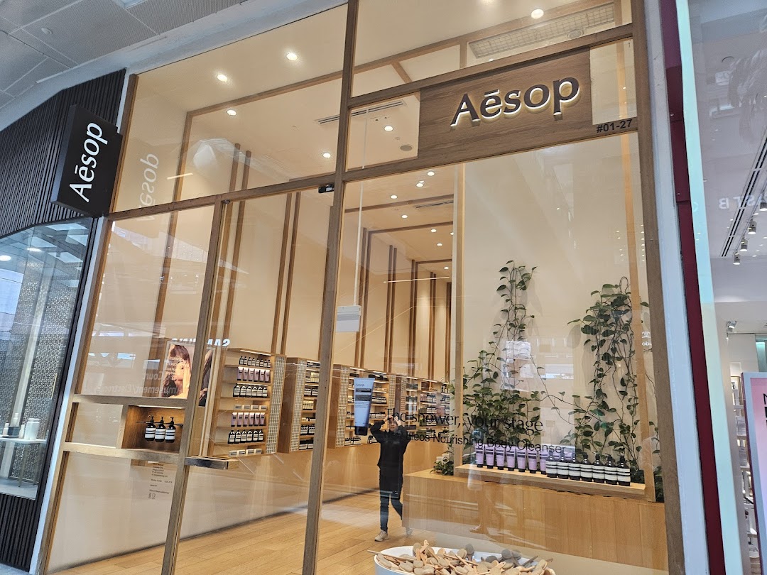 The elegant storefront of an Aesop boutique, showcasing its natural skincare and fragrance products through large glass windows.