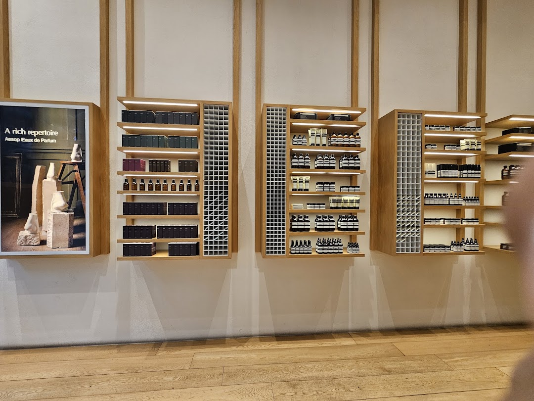 Aesop's minimalist interior features beautifully arranged skincare and fragrance products on wooden shelves.
