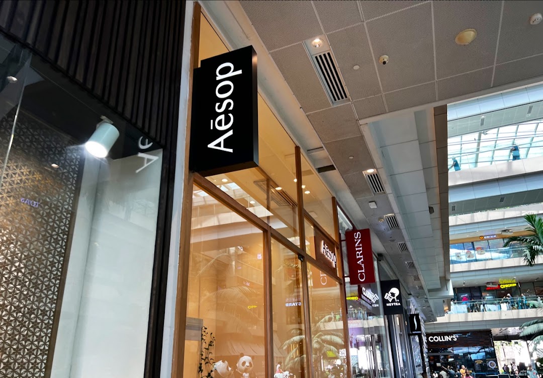 The exterior of an Aesop store with its prominent black and white sign in a modern shopping mall.