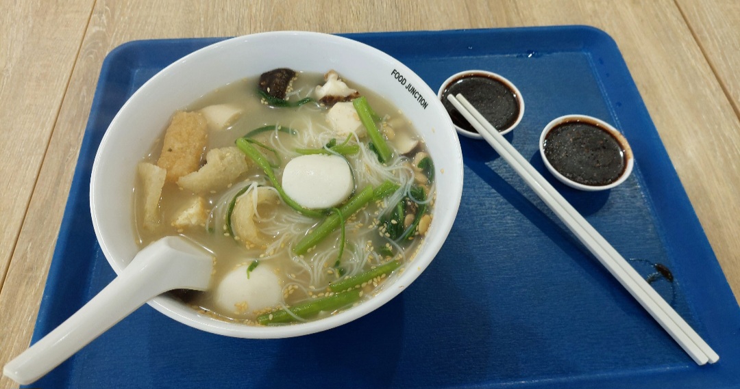 A delicious bowl of Yong Tau Foo with noodles, vegetables, and fishballs, served with dipping sauces.